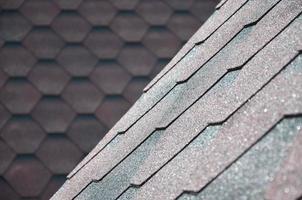 The texture of the roof with bituminous coating. Rough bituminous mosaic of red and brown flowers. Waterproof roofing photo