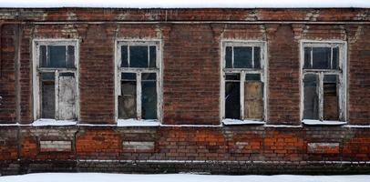 An old brick wall of an apartment house with a lot of boarded up windows without glass photo