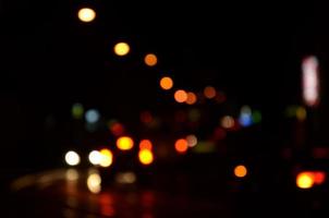 escena nocturna borrosa de tráfico en la carretera. imagen desenfocada de coches que viajan con faros luminosos. arte bokeh foto