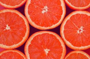 Top view of a several grapefruit slices on bright background in pink color. A saturated citrus texture image photo