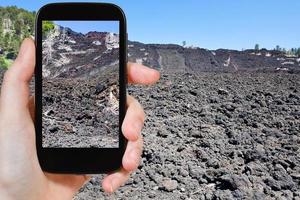 tourist taking photo of lava flow on slope of Etna