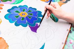 painter paints batik with floral pattern on silk photo