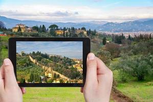 turista tomando fotos de verdes colinas en toscana