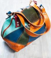 patchwork leather travel bag on wooden table photo