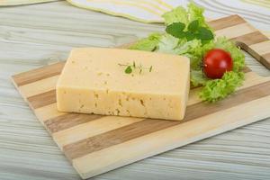 Yellow cheese on wooden board and wooden background photo