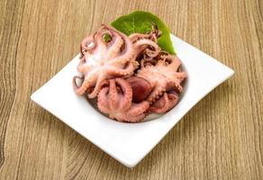 Marinated octopus in a bowl on wooden background photo