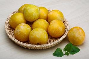 Yellow plums in a basket on wooden background photo