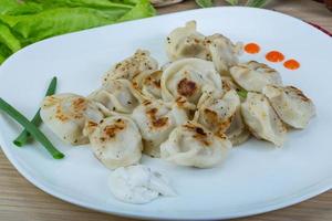 Roasted pierogi on the plate and wooden background photo