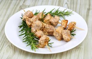 brochetas de pollo en el plato y fondo de madera foto