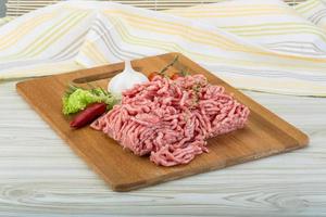 Minced meat on wooden board and wooden background photo