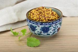 French mustard in a bowl on wooden background photo