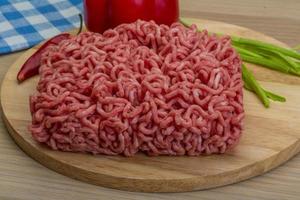 Minced meat on wooden board and wooden background photo