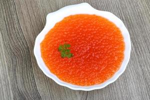 Red caviar in a bowl on wooden background photo