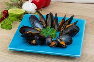 mejillones en el plato y fondo de madera foto