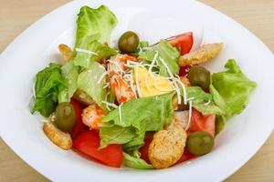 Caesar salad on the plate and wooden background photo