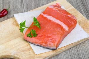 Salmon fillet on wooden board and wooden background photo