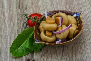 Champiñón en escabeche en un recipiente sobre fondo de madera foto