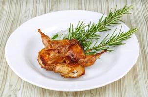 Grilled quail on the plate and wooden background photo