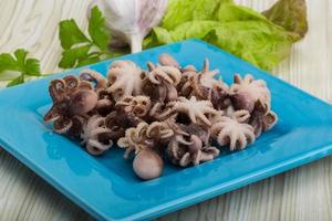 Boiled octopus on the plate and wooden background photo