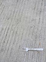 A plastic fork litter on top of a concrete road. Ab photo