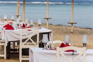 Mesas puestas festivas en la playa cerca del mar detalle foto