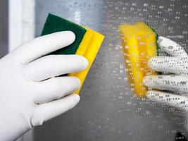 Mirror cleaning process. Hand in a white glove with a yellow sponge in it photo