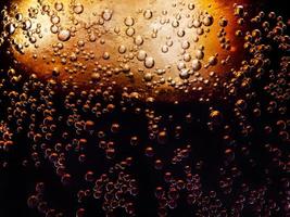 macro photo of the texture of bubbles in a glass of refreshing cold cola with ice