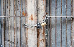 Close up photo of old doors with bars closed on a chain with a padlock