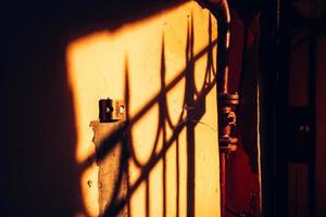 the shadow of the lattice on the old wall in the rays of the setting sun. photo