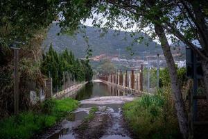 vista de la montaña a través del callejón con un charco enorme y vallas de huertos a los lados foto