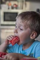 chico lindo comiendo sandía en casa. emociones reales sin posar. foto