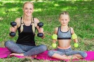 Woman with girl are training in the park. photo