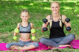 Woman with girl are training in the park. photo