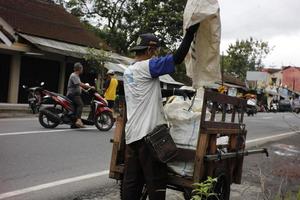 Magelang ,Indonesia 07 10 2022. You are cleaning up trash by putting it in an old wooden cart. photo