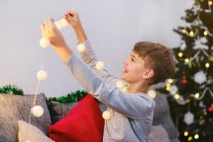 Portrait of a Christmas boy with Christmas lights in his hands. photo