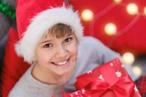 Portrait of a Christmas child in a Santa Claus hat with a Christmas present in his hands photo