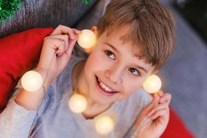 Close-up portrait of a Christmas child with Christmas lights in his hands photo