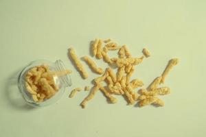 Crispy and delicious snack made of corn in a glass bottle on a plain green background photo