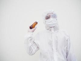 retrato de médico o científico con uniforme de suite de ppe sosteniendo una botella de plástico con un producto para el cuidado de la piel. covid-19 concepto aislado fondo blanco foto