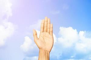 Young man hand showing refusal gesture behind of  blue sky and clouds background with copy space for wallpaper or banner photo