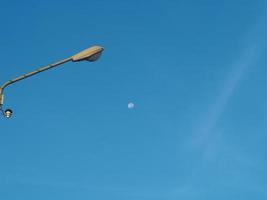 The street light tower on the background is blue sky And there is a small moon in the middle photo