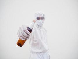 retrato de médico o científico con uniforme de suite de ppe sosteniendo una botella de plástico con un producto para el cuidado de la piel. covid-19 concepto aislado fondo blanco foto