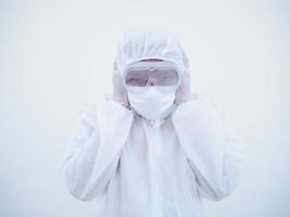 Asian doctor or scientist in PPE suite uniform covers ears with hands. Danger of coronavirus or COVID-19 concept isolated white background photo