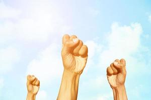 Raised fist of success behind of  blue sky and clouds background with copy space for wallpaper or banner photo