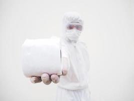 Asian male doctor or scientist in PPE suite uniform holding toilet paper. Lack of toilet paper in the quarantine of coronavirus. COVID-19 concept isolated white background photo