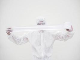 Asian male doctor or scientist in PPE suite uniform holding toilet paper. Lack of toilet paper in the quarantine of coronavirus. COVID-19 concept isolated white background photo