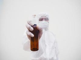 retrato de médico o científico con uniforme de suite de ppe sosteniendo una botella de plástico con un producto para el cuidado de la piel. covid-19 concepto aislado fondo blanco foto