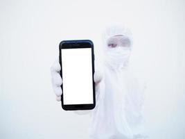 Young doctor or scientist in PPE suite uniform holding a smart phone with blank white screen for text or design. coronavirus or COVID-19 concept isolated white background photo