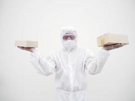 joven con uniforme de suite de ppe mientras sostiene cajas de cartón con guantes médicos de goma y máscara. concepto de coronavirus o covid-19 fondo blanco aislado foto