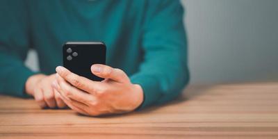 Closeup image of a man holding and using mobile phone or smartphone in room. photo